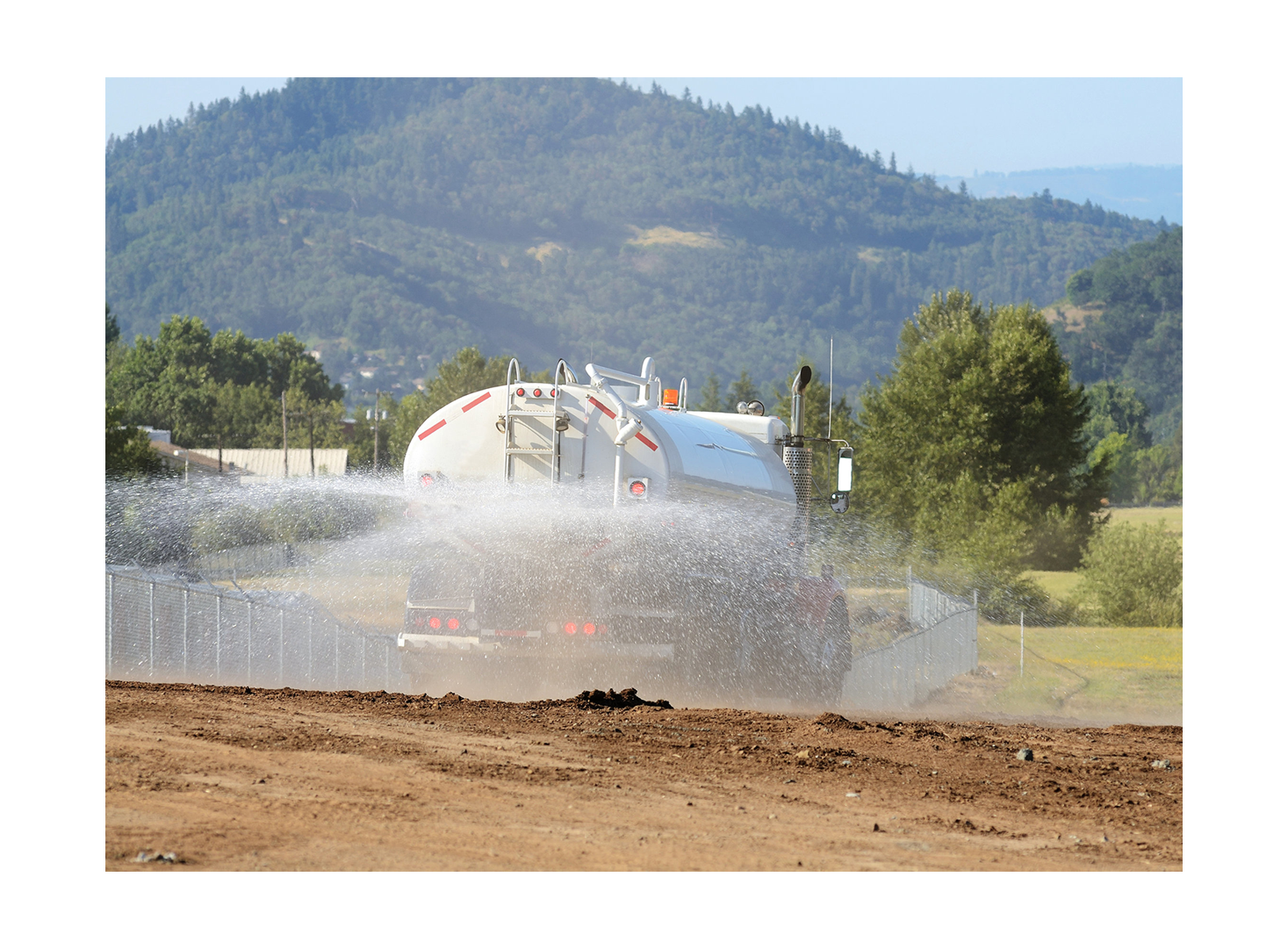 Meenderinck LLC truck spraying water over dirt at construction site